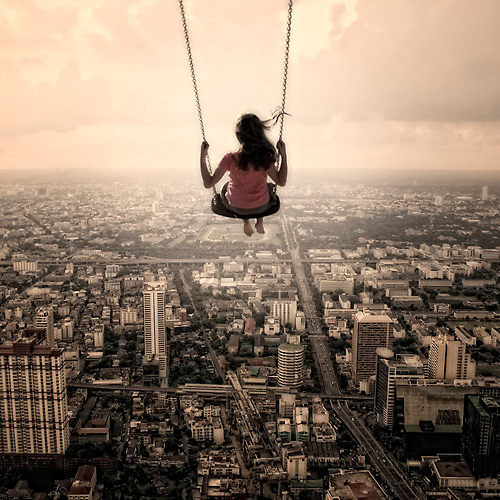 girl on swing overlooking a city